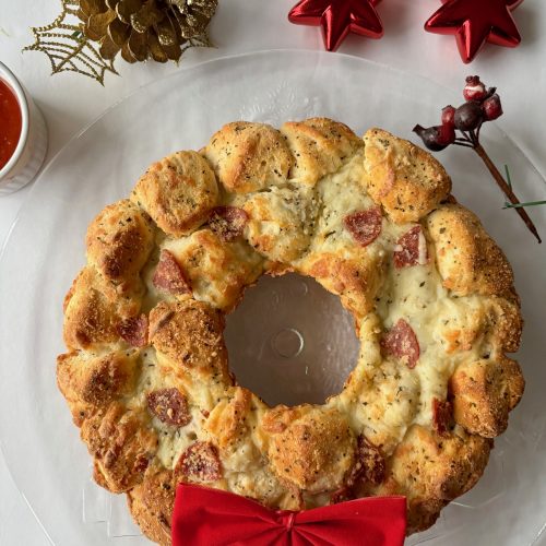 Pizza bread in the shape of a wreath, with a red bow at the bottom.